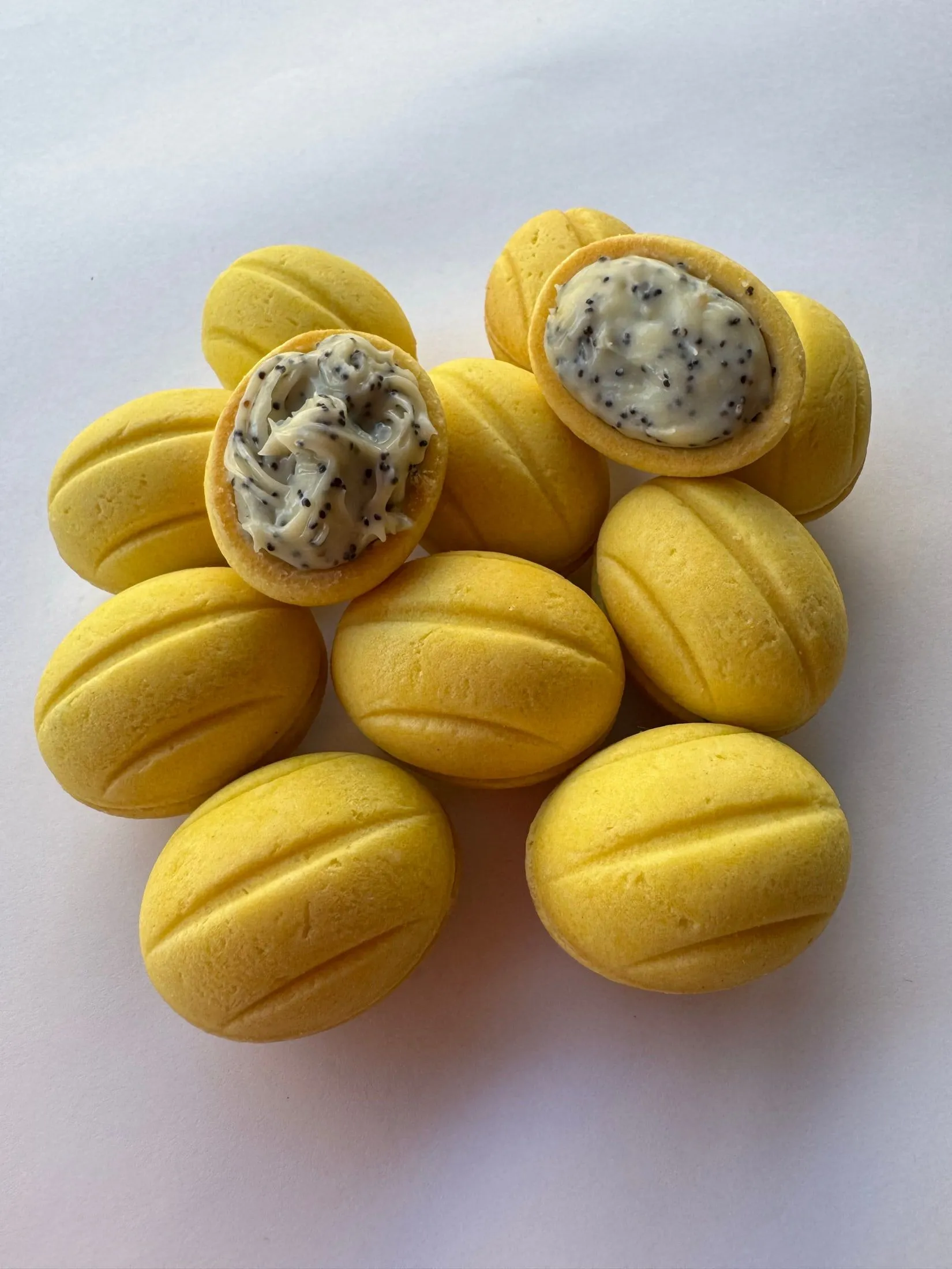 Oreshki amarillos apilados, dos abiertos con relleno de crema y semillas de amapola